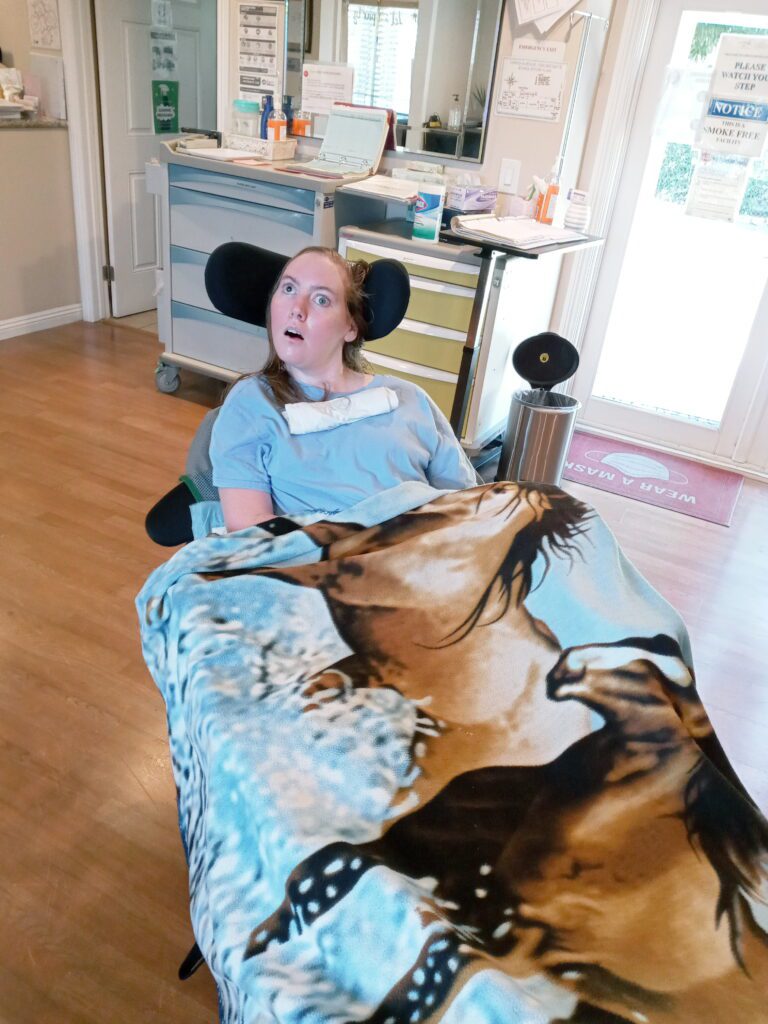 A girl sitting on top of a bed with a horse blanket.