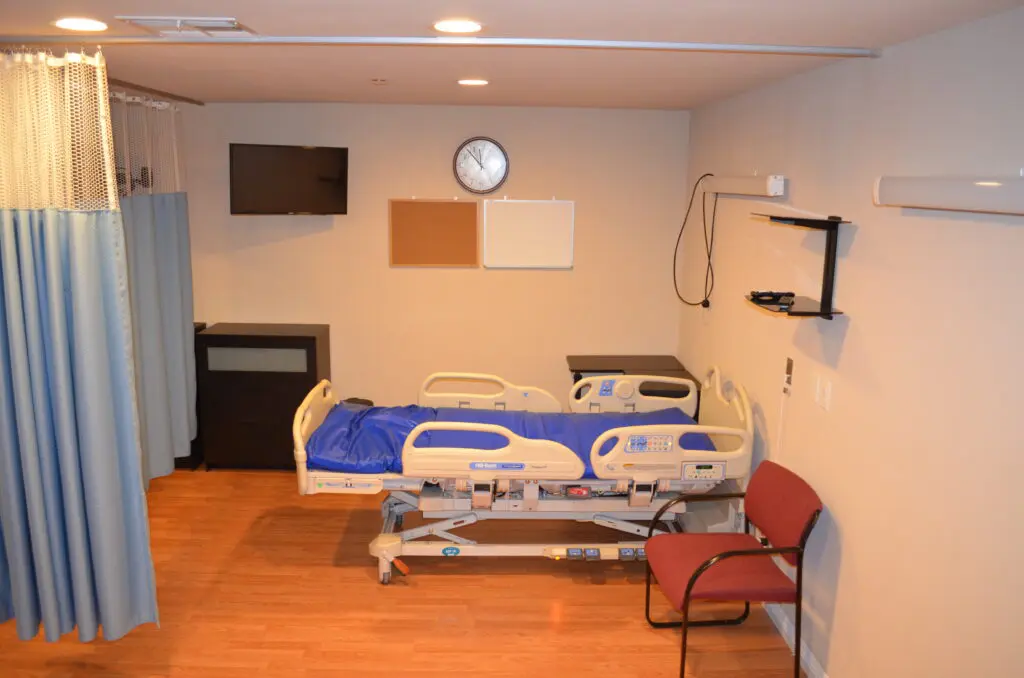 A hospital room with two beds and a television.