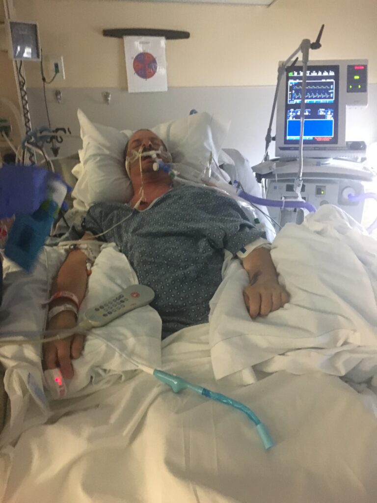 A man in hospital bed with oxygen mask on.